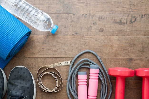 Vlakke lay-out van sport apparatuur en fles water en meetlint op houten achtergrond met kopie ruimte