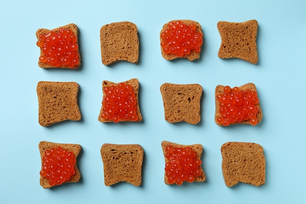 Vlakke leggen met sneetjes brood met kaviaar op blauwe achtergrond