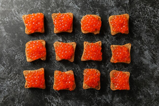 Vlakke leggen met sneetjes brood met kaviaar op zwarte smokey achtergrond