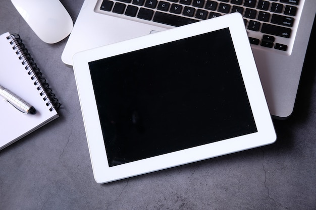 Vlakke samenstelling van digitale tablet, laptop en stationair kantoor op zwarte achtergrond