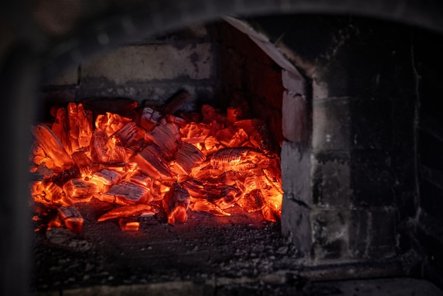 Vlam van vuur van hete brandende kolen in de open haard Warmte uit de oven