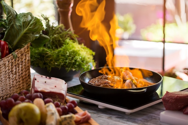 Vlammen in koekenpan. Stuk vlees wordt gebakken. Bewezen recept van geflambeerde steak. Asperges omwikkeld met spekreepjes.