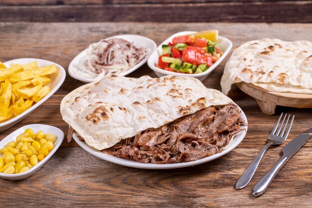 Vlees doner kebab op het bord Turkse vlees doner kabab op houten achtergrond Gediend met hete lavash Traditionele Turkse keuken van dichtbij