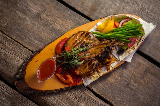 Vlees en kom met saus verse groenten en dunne pita lunch op rustieke tafel varkensvlees gekookt op een grill