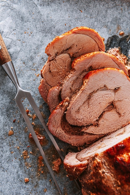 Vlees gebakken op een bakplaat en bakpapier naast een vleesvork