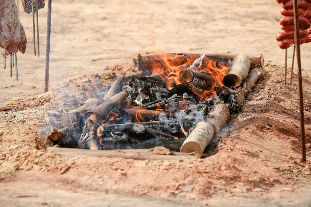 Vlees gebraden en gesneden op tafel en kampvuur met brandhout in gaucho-stijl