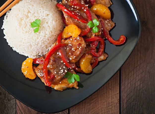 Vlees in een pittige saus, paprika en mandarijnen met een garnituur van gekookte rijst