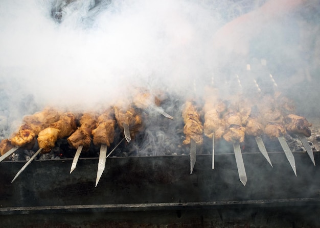 Vlees kookt op hete kolen in de rook Picknick in de natuur Varkensvlees wordt gebakken op de grill