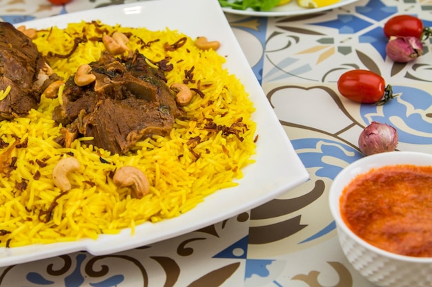 Vlees Quzi of Ghozi biryani rijst met cashewnoot geserveerd in een gerecht geïsoleerd op tafel uitzicht op Arabisch eten