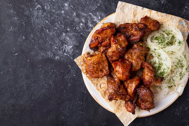 Vlees shish kebab met ui en lavash op een bord. Bovenaanzicht, tekstruimte