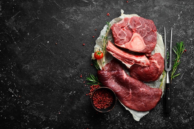 Vlees Verse rauwe kalfssteaks en vlees Bovenaanzicht Platliggend bovenaanzicht op zwarte stenen snijtafel