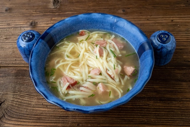 Vleesbouillonsoep met noedels in een blauwe kom Serveersoep voor de lunch