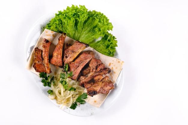 Vleeskebab op ribben op lavash met uien en kool op een witte plaat, op een afgelegen witte achtergrond