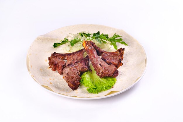 Vleeskebab op ribben op lavash met uien en kool op een witte plaat, op een afgelegen witte achtergrond.