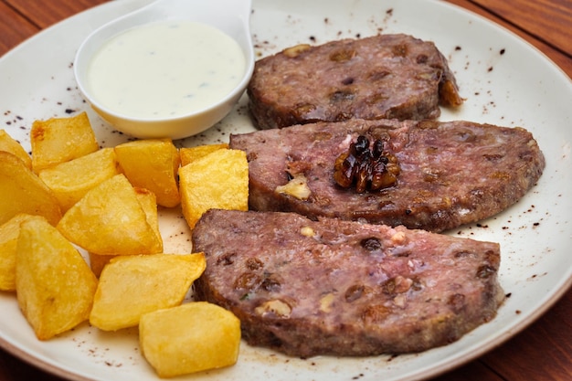 Vleeskoteletten met gebakken aardappelen op een bord met saus