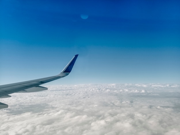 vleugel van het vliegtuig op witte wolken