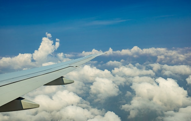 Vleugel van het vliegtuig over witte wolken. Vliegtuig dat op blauwe hemel vliegt. Schilderachtig uitzicht vanuit vliegtuig raam. Commerciële luchtvaartmaatschappij vlucht. Vliegtuigvleugel boven wolken.