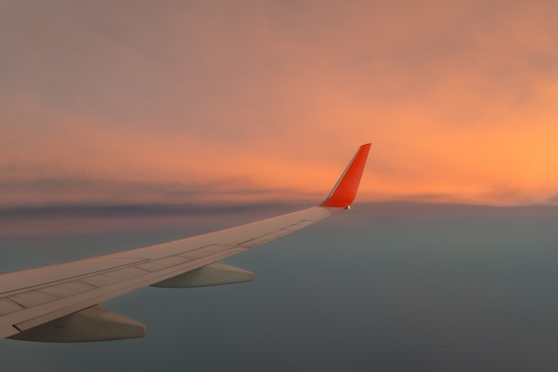 Vleugelvliegtuig tegen de zonsonderganghemel boven de wolk.