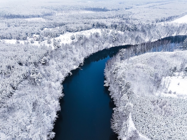 Vliegen boven de rivier de Brda en het besneeuwde bos in de winter in Polen