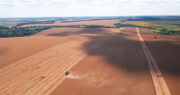 Vliegen boven luchtfoto van het oogsten van tarwevelden met maaidorser