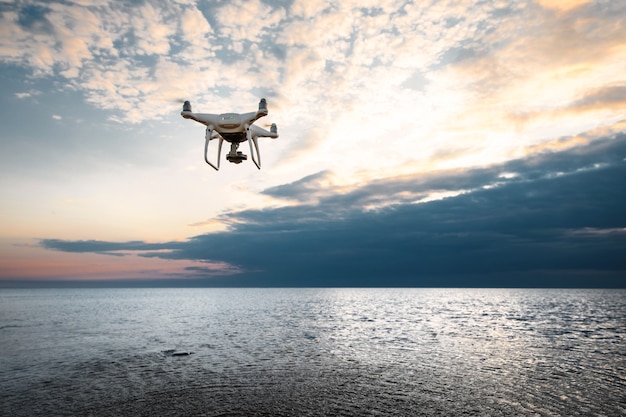 Vliegende drone op een achtergrond van zee zonsondergang