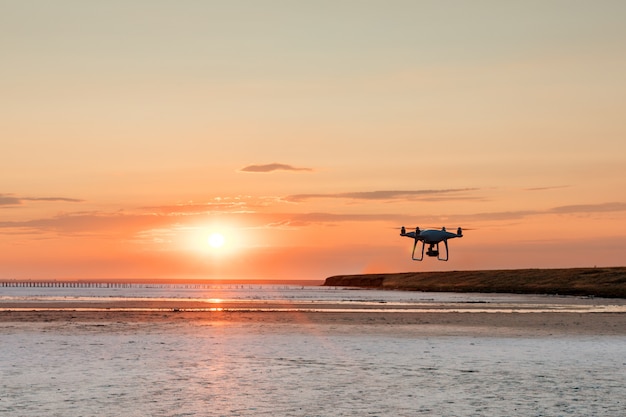 Vliegende drone op een oppervlak van zee zonsondergang