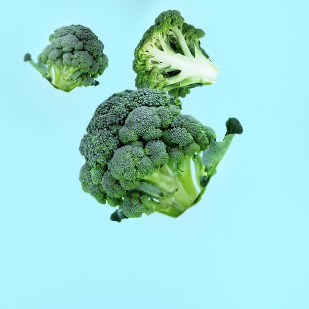 Vliegende groene broccolischijfjes op een blauwe achtergrond