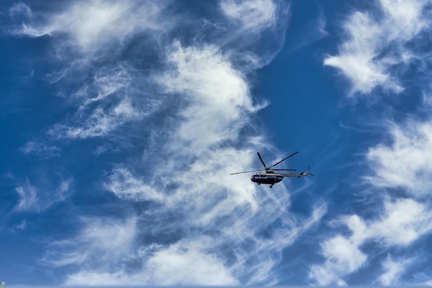 Vliegende helikopter op de achtergrond van wolken en blauwe lucht