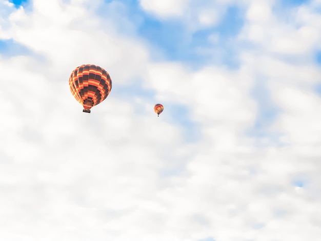 Vliegende in de lucht vele helder gekleurde prachtige ballonnen in de lucht in cappadocië in de bergen vroeg bij zonsopgang ochtend vullen ballon met warme lucht uit brander grote mand toeristen excursie wolk vlucht