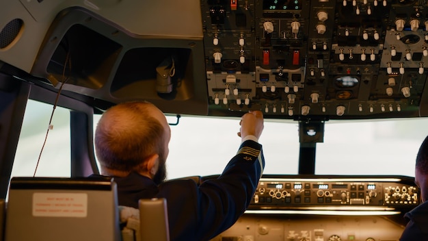Vliegende vliegtuigbemanning bereidt zich voor om op te stijgen met vliegtuig in cockpit, met behulp van de opdracht op het bedieningspaneel en dashboardknoppen voor navigatie. Voorruit en motor met handvat en hendel om te vliegen.