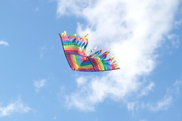 Foto vlieger in een blauwe hemel regenboog delta vlieger die tussen de wolken vliegt gelukkige groeiende jaren moment buiten tijd doorbrengen aspiraties doel inspiratie concept vrijheid en zomervakantie jeugd droom