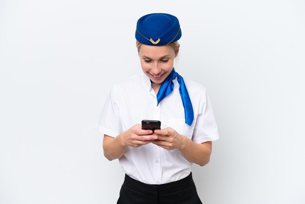 Vliegtuig blonde stewardess vrouw geïsoleerd op een witte achtergrond die een bericht verzendt met de mobiel