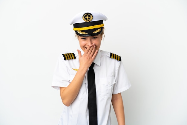 Vliegtuig blonde vrouw piloot geïsoleerd op een witte achtergrond gelukkig en lachend die mond bedekken met hand