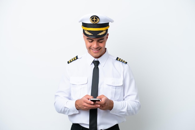 Vliegtuig piloot blanke man geïsoleerd op een witte achtergrond die een bericht verzendt met de mobiel