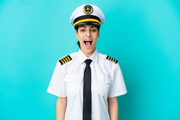 Vliegtuig piloot blanke vrouw geïsoleerd op blauwe achtergrond met verrassing gezichtsuitdrukking