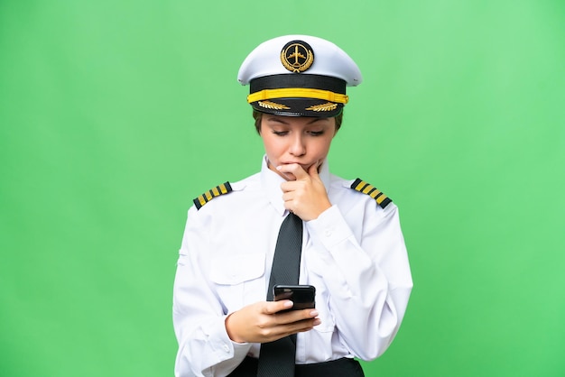 Vliegtuig piloot vrouw over geïsoleerde chroma key achtergrond denken en een bericht verzenden