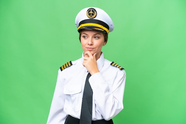 Vliegtuig piloot vrouw over geïsoleerde chroma key achtergrond kijkend naar de zijkant