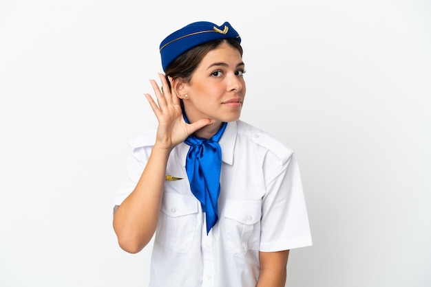 Vliegtuig stewardess blanke vrouw geïsoleerd op een witte achtergrond luisteren naar iets door hand op het oor te leggen