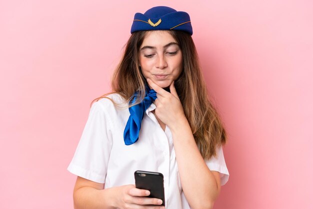 Vliegtuig stewardess blanke vrouw geïsoleerd op roze achtergrond denken en het verzenden van een bericht