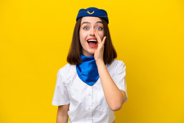 Vliegtuig stewardess Oekraïense vrouw geïsoleerd op gele achtergrond schreeuwend met haar mond wijd open