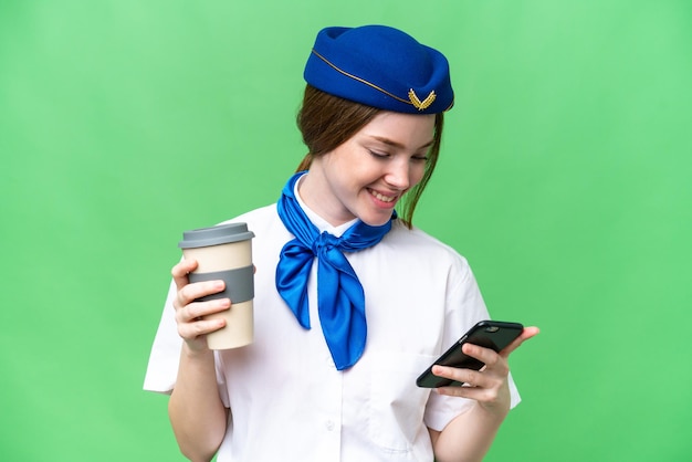 Vliegtuig stewardess over geïsoleerde chroma key achtergrond met koffie om mee te nemen en een mobiel