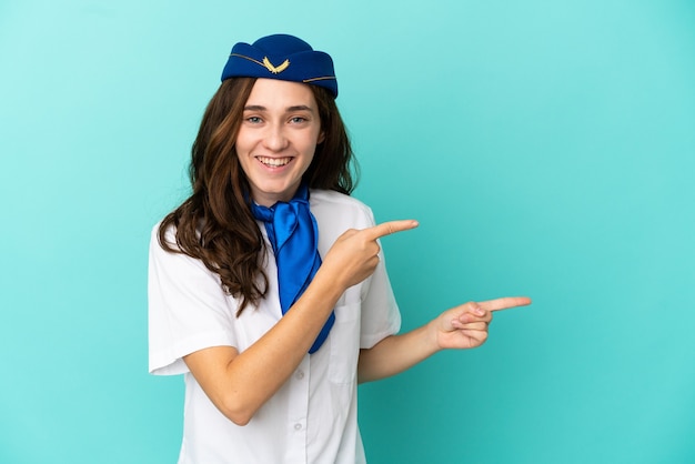 Vliegtuig stewardess vrouw geïsoleerd op blauwe achtergrond verrast en wijzende kant