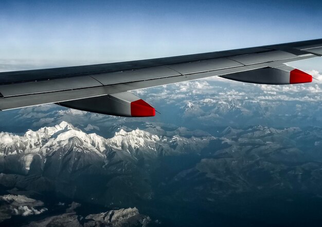 Foto vliegtuig vliegt over een met sneeuw bedekte berg tegen de lucht