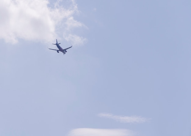 Vliegtuig vliegt weg in de verte tegen een blauwe lucht