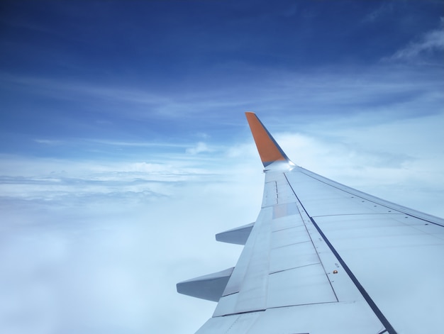 Vliegtuigenvleugel over blauwe hemel en witte wolken, Mening van venster tijdens vlucht