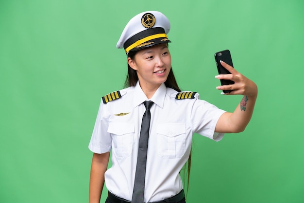 Vliegtuigpiloot Aziatische vrouw over geïsoleerde achtergrond die een selfie maakt