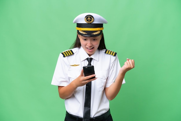 Vliegtuigpiloot Aziatische vrouw over geïsoleerde achtergrond verrast en stuurt een bericht