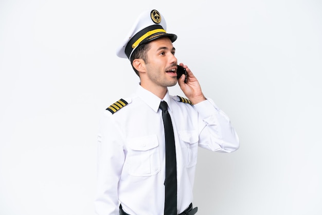 Vliegtuigpiloot over geïsoleerde witte achtergrond die een gesprek met de mobiele telefoon houdt