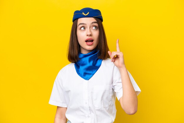 Vliegtuigstewardess Oekraïense vrouw geïsoleerd op gele achtergrond denken een idee met de vinger omhoog