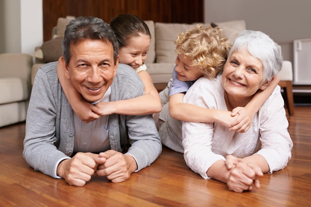 Vloer meeliften of portret van grootouders met gelukkige kinderen spelen of knuffelen met liefde in het ouderlijk huis Bejaarde oma of leuke oude man ontspannen of hechten om te genieten van tijd met kinderen met pensioen